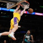 
              Los Angeles Lakers guard Austin Reaves, left, dunks as Portland Trail Blazers forward Jabari Walker defends during the first half of an NBA basketball game Wednesday, Nov. 30, 2022, in Los Angeles. (AP Photo/Mark J. Terrill)
            