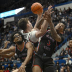 Connecticut center Donovan Clingan, center, is fouled while reaching for a rebound by Delaware State guard Martaz Robinson, right, as Delaware State forward Ronald Lucas, bottom, defends during the first half of an NCAA college basketball game, Sunday, Nov. 20, 2022, in Hartford, Conn. (AP Photo/Jessica Hill)
