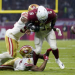 Arizona Cardinals running back James Conner, right, loses control of the ball as he is hit by San Francisco 49ers quarterback Trey Lance, above, and cornerback Charvarius Ward, below, during the first half of an NFL football game Monday, Nov. 21, 2022, in Mexico City. (AP Photo/Marcio Jose Sanchez)