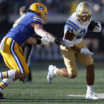 UCLA running back Zach Charbonnet (24) runs against California linebacker Jackson Sirmon (8) during the first half of an NCAA college football game in Berkeley, Calif., Friday, Nov. 25, 2022. (AP Photo/Jed Jacobsohn)