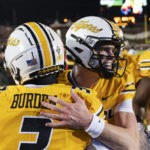 Missouri quarterback Brady Cook, center, hugs Luther Burden, left, after Burden scored a touchdown during the first quarter of the team's NCAA college football game against New Mexico State Saturday, Nov. 19, 2022, in Columbia, Mo. (AP Photo/L.G. Patterson)