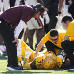 Arizona State head coach Shaun Aguano, left, checks on injured Arizona State defensive lineman B.J. Green II (35) as Green receives medical attention during the first half of an NCAA college football game against Oregon State in Tempe, Ariz., Saturday, Nov. 19, 2022. Oregon State won 31-7. (AP Photo/Ross D. Franklin)