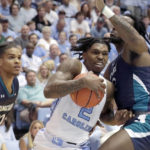 
              North Carolina guard Caleb Love (2) drives against UNC Wilmington guard Shykeim Phillips (20) and center Victor Enoh (12) during the first half of an NCAA college basketball game in Chapel Hill, N.C., Monday, Nov. 7, 2022. (AP Photo/Chris Seward)
            