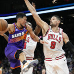 
              Phoenix Suns guard Devin Booker (1) is stopped on a drive to the basket by Chicago Bulls center Nikola Vucevic (9) and Bulls forward Patrick Williams, second from right, as Bulls guard Zach LaVine, left, looks on during the first half of an NBA basketball game in Phoenix, Wednesday, Nov. 30, 2022. (AP Photo/Ross D. Franklin)
            