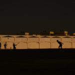 People play cricket in the streets in Doha, Qatar, Friday, Nov. 25, 2022. As dawn broke Friday as Qatar hosts the World Cup, the laborers who built this energy-rich country's stadiums, roads and rail filled empty stretches of asphalt and sandlots to play cricket. (AP Photo/Abbie Parr)