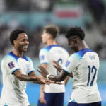 England's Bukayo Saka , right, celebrates with a teammate after scoring his side's fourth goal against Iran during the World Cup group B soccer match between England and Iran at the Khalifa International Stadium, in Doha, Qatar, Monday, Nov. 21, 2022. (AP Photo/Martin Meissner)