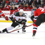 Arizona Coyotes center Nick Bjugstad (17) battles for the puck against New Jersey Devils center Yegor Sharangovich (17) and New Jersey Devils defenseman Brendan Smith (2) during the second period of an NHL hockey game, Saturday, Nov. 12, 2022, in Newark, N.J. (AP Photo/Noah K. Murray)