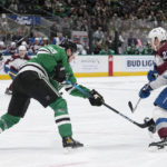 Dallas Stars defenseman Esa Lindell (23) attempts to clear the puck that Colorado Avalanche center Nathan MacKinnon (29) blocks with his skate in the second period of an NHL hockey game Monday, Nov. 21, 2022, in Dallas. (AP Photo/Tony Gutierrez)