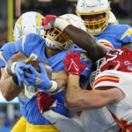 Los Angeles Chargers running back Austin Ekeler, left, scores a touchdown as he is face masked by Kansas City Chiefs linebacker Nick Bolton as linebacker Leo Chenal, right, tries to stop him during the first half of an NFL football game Sunday, Nov. 20, 2022, in Inglewood, Calif. (AP Photo/Jae C. Hong)