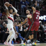 Portland Trail Blazers guard Damian Lillard, left, looks for an open teammate past Miami Heat guards Gabe Vincent (2) and Max Strus (31) during the second half of an NBA basketball game, Monday, Nov. 7, 2022, in Miami. (AP Photo/Wilfredo Lee)