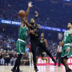Cleveland Cavaliers guard Donovan Mitchell (45) shoots between Boston Celtics center Al Horford (42) and forward Jayson Tatum (0) during the first half of an NBA basketball game Wednesday, Nov. 2, 2022, in Cleveland. (AP Photo/Ron Schwane)