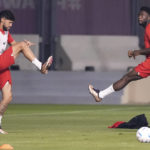 
              Canada forward Alphonso Davies, right, stretches his leg next to teammate Jonathan Osorio during practice at the World Cup in Doha, Qatar, on Monday, Nov. 21, 2022. (Nathan Denette/The Canadian Press via AP)
            