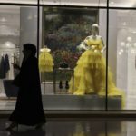 
              A woman passes by fashion outfit at the Al Hazm luxury mall, in Doha, Qatar, Wednesday, April 24, 2019. After FIFA awarded the World Cup to Qatar, there were questions about what women would be allowed to wear. The local organizing guide says women must dress modestly with sleeves, long pants or long skirts. 
 (AP Photo/Kamran Jebreili)
            