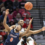 
              Cal State Fullerton guard Jalen Harris (0) and San Diego State guard Lamont Butler (5) fight for the ball during the first half of an NCAA college basketball game Monday, Nov. 7, 2022, in San Diego. (AP Photo/Denis Poroy)
            