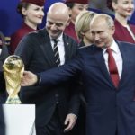 FILE - Russian President Vladimir Putin touches the World Cup trophy as FIFA President Gianni Infantino stands beside him, at the end of the final match between France and Croatia at the 2018 soccer World Cup in the Luzhniki Stadium in Moscow, Russia, Sunday, July 15, 2018. Russia hosted the World Cup party in 2018 but now it's off the guest list. (AP Photo/Petr David Josek, File)