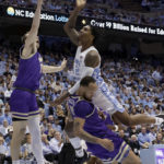 North Carolina guard Caleb Love (2) drives against James Madison guard Noah Freidel, left, and James Madison guard Takal Molson, bottom, during the first half of an NCAA college basketball game Sunday, Nov. 20, 2022, in Chapel Hill, N.C. Love was called for a foul on the play. (AP Photo/Chris Seward)
