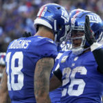 New York Giants running back Saquon Barkley (26) celebrates with wide receiver Isaiah Hodgins after scoring a touchdown against the Houston Texans during the fourth quarter of an NFL football game, Sunday, Nov. 13, 2022, in East Rutherford, N.J. (AP Photo/John Minchillo)
