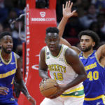 
              Houston Rockets forward Usman Garuba (16) looks to drive past Golden State Warriors forwards JaMychal Green, left, and Anthony Lamb (40) during the first half of an NBA basketball game Sunday, Nov. 20, 2022, in Houston. (AP Photo/Michael Wyke)
            
