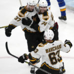 Boston Bruins center Patrice Bergeron (37) embraces left wing Jake DeBrusk (74) after Bergeron's goal against the St. Louis Blues during the third period of an NHL hockey game, Monday, Nov. 7, 2022, in Boston. The Bruins won 3-1. At bottom is Bruins left wing Brad Marchand. (AP Photo/Charles Krupa)