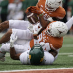 
              Texas linebacker Trevell Johnson, top, and defensive back Terrance Brooks, center, break up a pass intended for Baylor wide receiver Jaylen Ellis, bottom, during the first half of an NCAA college football game in Austin, Texas, Friday, Nov. 25, 2022. (AP Photo/Eric Gay)
            