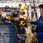 
              Ross Brown places flowers on a memorial for three slain University of Virginia football players on Saturday, Nov. 19, 2022, at John Paul Jones Arena on the university's campus in Charlottesville, Va. On Sunday, Nov. 13, University of Virginia football players Devin Chandler, Lavel Davis Jr. and D'Sean Perry were shot and killed by a teammate following a school field trip to Washington. (Shaban Athuman/Richmond Times-Dispatch via AP)
            