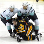 
              Pittsburgh Penguins' Ryan Poehling (25) is checked by Seattle Kraken's Jamie Oleksiak (24) and Shane Wright (51) during the first period of an NHL hockey game in Pittsburgh, Saturday, Nov. 5, 2022. (AP Photo/Gene J. Puskar)
            