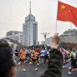 
              In this photo released by Xinhua News Agency, a spectator waves a national flag as runners compete in the Beijing Marathon in Beijing, Sunday, Nov. 6, 2022. Thousands of runners took to the streets of China's capital on Sunday for the return of the Beijing marathon after a two-year hiatus because of COVID-19, even as another death blamed on China's strict pandemic controls generated more public anger. (Song Yanhua/Xinhua via AP)
            