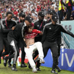 
              Security personnel remove a pitch invader who ran to the field during a World Cup group D soccer match between Tunisia and France at the Education City Stadium in Al Rayyan, Qatar, Wednesday, Nov. 30, 2022. (AP Photo/Martin Meissner)
            