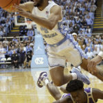 North Carolina guard R.J. Davis (4) manages to get a pass off as he stumbles over James Madison guard Xavier Brown during the second half of an NCAA college basketball game, Sunday, Nov. 20, 2022, in Chapel Hill, N.C. (AP Photo/Chris Seward)