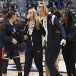 Connecticut's Nika Muhl, left, Paige Bueckers, center, and Dorka Juhasz, second from right, walk off the court during a medical emergency involving Associate Head Coach Chris Dailey before an NCAA basketball game against North Carolina State, Sunday, Nov. 20, 2022, in Hartford, Conn. (AP Photo/Jessica Hill)