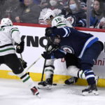 Winnipeg Jets' Neal Pionk (4) fights for the puck along the boards with Dallas Stars' Miro Heiskanen (4) and Joe Pavelski (16) during the third period of an NHL hockey game, Tuesday, Nov. 8, 2022 in Winnipeg, Manitoba. (Fred Greenslade/The Canadian Press via AP)