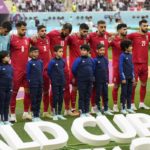 The team of Iran standing on the pitch waiting for the national anthem prior to the the World Cup group B soccer match between England and Iran at the Khalifa International Stadium, in Doha, Qatar, Monday, Nov. 21, 2022. (AP Photo/Martin Meissner)