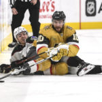 Arizona Coyotes right wing Clayton Keller and Vegas Golden Knights center Nicolas Roy (10) hit the ice while chasing the puck during the second period of an NHL hockey game Thursday, Nov. 17, 2022, in Las Vegas. (AP Photo/Sam Morris)