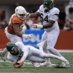 
              Baylor quarterback Blake Shapen (12) is tripped up by Texas defensive lineman Alfred Collins (95) during the first half of an NCAA college football game in Austin, Texas, Friday, Nov. 25, 2022. (AP Photo/Eric Gay)
            