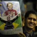 
              A fan of British Mercedes Formula One driver Lewis Hamilton holds his image, under that of late Brazilian driver Ayrton Senna during a ceremony where Hamilton received the title of Honorary Citizen of Brazil at the Chamber of Deputies in Brasilia, Brazil, Monday, Nov. 7, 2022. (AP Photo/Eraldo Peres)
            