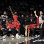 
              Portland Trail Blazers forward Jerami Grant (9) follows through on his 3-point shot as Brooklyn Nets forward Royce O'Neale (00) watches and the Trail Blazers bench reacts during the first half of an NBA basketball game Sunday, Nov. 27, 2022, in New York. (AP Photo/Jessie Alcheh)
            