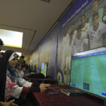 
              A woman plays a soccer game on a screen in front of a photo of Team USA at a cultural center prior to watching Iran's national soccer team play against the United States in Qatar's soccer World Cup in Tehran, Iran, Tuesday, Nov. 29, 2022. (AP Photo/Vahid Salemi)
            