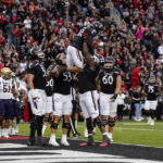 Cincinnati wide receiver Tyler Scott, top, celebrates with teammates after scoring a touchdown during the first half of an NCAA college football game against Navy, Saturday, Nov. 5, 2022, in Cincinnati. (AP Photo/Jeff Dean)