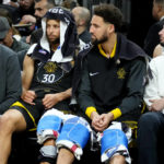 
              Golden State Warriors guard Stephen Curry, left, and guard Klay Thompson watch from the bench during the first half of an NBA basketball game against the Phoenix Suns, Wednesday, Nov. 16, 2022, in Phoenix. (AP Photo/Matt York)
            