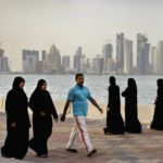 
              FILE- Qatari women and a man walk in front of the city skyline in Doha, Qatar, Saturday, April 7, 2012. The foreign fans descending on Doha for the 2022 FIFA World Cup will find a country where women work, hold public office and cruise in their supercars along the city's palm-lined corniche. (AP Photo/Kamran Jebreili, File)
            