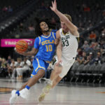 UCLA's Tyger Campbell (10) drives into Baylor's Caleb Lohner (33) during the first half of an NCAA college basketball game Sunday, Nov. 20, 2022, in Las Vegas. (AP Photo/John Locher)