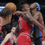 
              Oklahoma City Thunder guard Shai Gilgeous-Alexander, right, loses the ball as he is fouled by Chicago Bulls guard Ayo Dosunmu, center, during the first half of an NBA basketball game Friday, Nov. 25, 2022, in Oklahoma City. Bulls' DeMar DeRozan is at left. (AP Photo/Sue Ogrocki)
            
