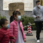 
              Children wearing masks walk by a sign which reads "Exit" at a COVID test station in Beijing, Sunday, Nov. 6, 2022. (AP Photo/Ng Han Guan)
            