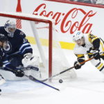 
              Pittsburgh Penguins' Josh Archibald (15) attempts a wraparound against Winnipeg Jets goaltender Connor Hellebuyck (37) as Jets' Josh Morrissey (44) also defends during first-period NHL hockey game action in Winnipeg, Manitoba, Saturday, Nov. 19, 2022. (John Woods/The Canadian Press via AP)
            