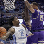 North Carolina guard Caleb Love (2) is defended by James Madison forward Alonzo Sule, center, and guard Takal Molson (15) during the first half of an NCAA college basketball game Sunday, Nov. 20, 2022, in Chapel Hill, N.C. (AP Photo/Chris Seward)