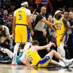 A referee stands between Los Angeles Lakers' Patrick Beverly and Phoenix Suns' Deandre Ayton, bottom left on the floor, after pushing him to the ground during the second half of an NBA basketball game in Phoenix, Tuesday, Nov. 22, 2022. Patrick Beverly was ejected from the game for the flagrant foul on Ayton. (AP Photo/Darryl Webb)