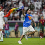 A pitch invader runs across the field with a rainbow flag during the World Cup group H soccer match between Portugal and Uruguay, at the Lusail Stadium in Lusail, Qatar, Monday, Nov. 28, 2022. (AP Photo/Abbie Parr)