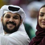 A couple on the tribune smiles to the camera prior the World Cup, group A soccer match between Qatar and Ecuador at the Al Bayt Stadium in Doha, Sunday, Nov. 20, 2022. (AP Photo/Natacha Pisarenko)