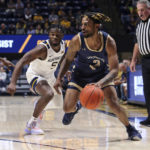 Mount St. Mary's guard Deandre Thomas (2) dribbles past West Virginia guard Joe Toussaint (5) during the first half of an NCAA college basketball game in Morgantown, W.Va., Monday, Nov. 7, 2022. (AP Photo/Kathleen Batten)