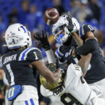 The football flies past Wake Forest's A.T. Perry and Duke's Chandler Rivers into the hands of Darius Joiner (1) for an interception late in the second half of an NCAA college football game in Durham, N.C., Saturday, Nov. 26, 2022. (AP Photo/Ben McKeown)